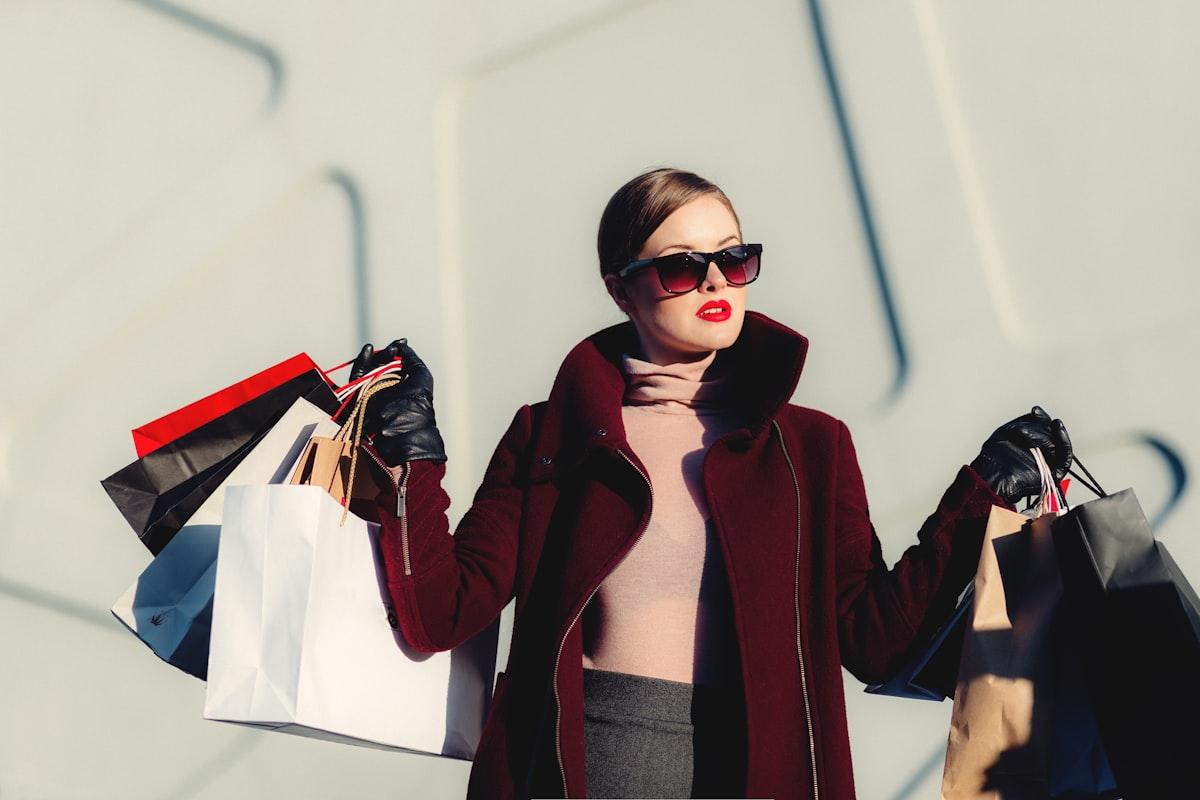 A model wearing the Éclat Noir black tailored coat beside a rail of the collection